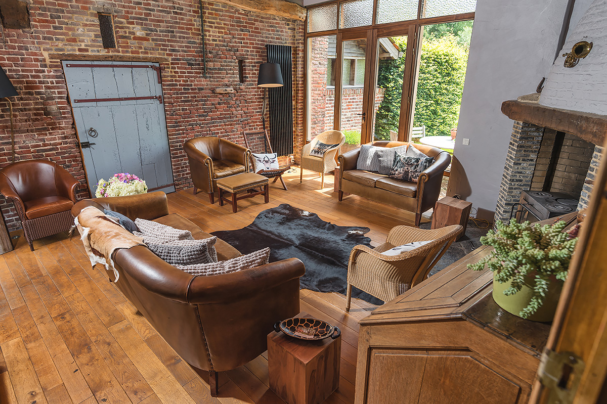 gezellig salon met lederen zetels in onze authentieke vakantiewoning in de vlaamse ardennen